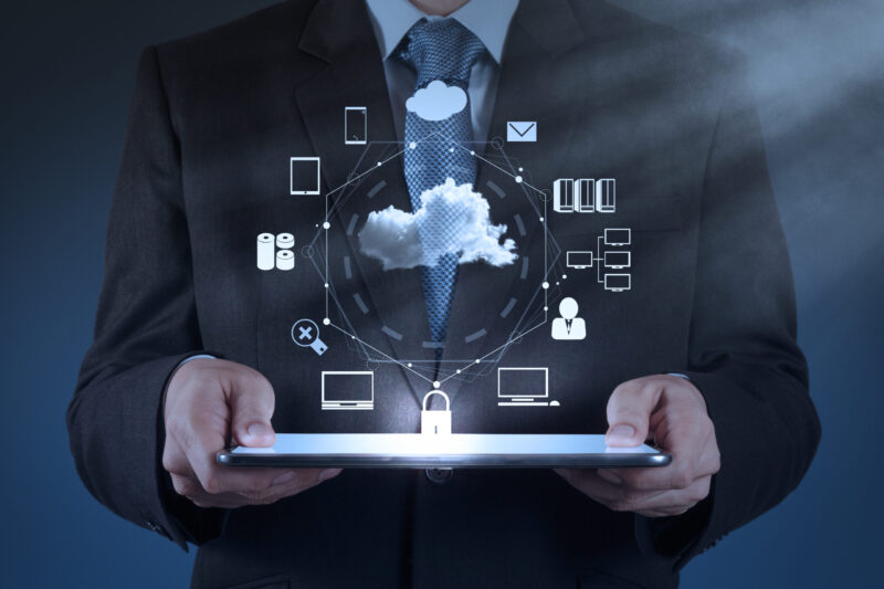 IT Consultancy and Project Management services. Man in suit holding a tablet. Image of a cloud with lots of services is being projected above the laptop